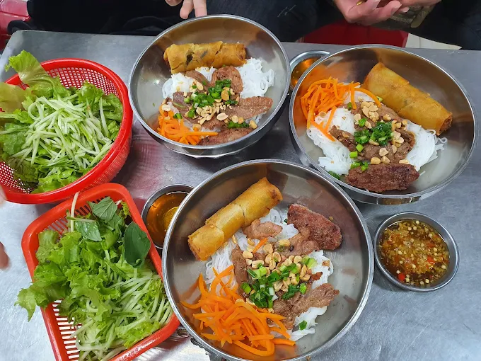 Grilled pork vermicelli bowls with spring rolls and fresh greens