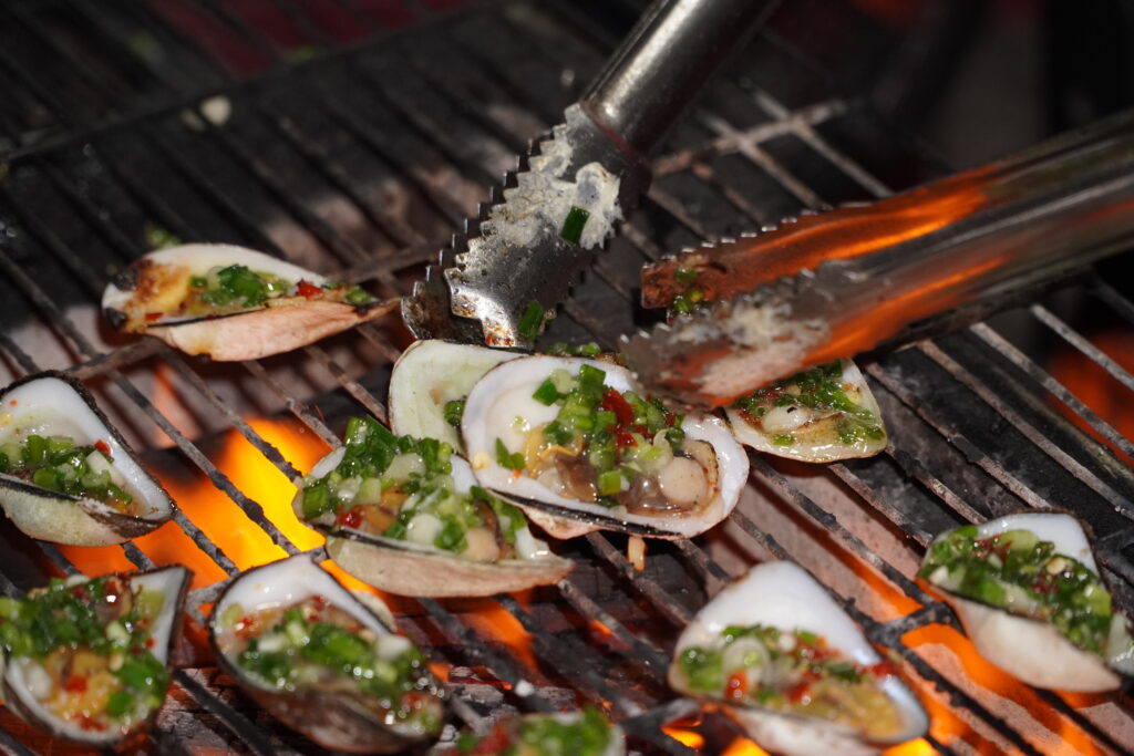 Grilled scallops with scallion oil and chopped chili on charcoal grill