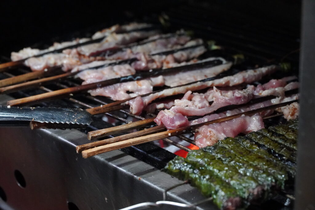 Grilled Vietnamese betel leaf rolls sizzling over charcoal