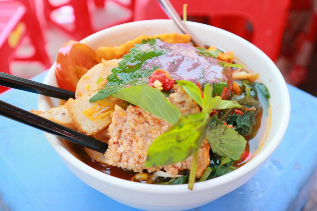 Vietnamese crab noodle soup with herbs and tomato broth