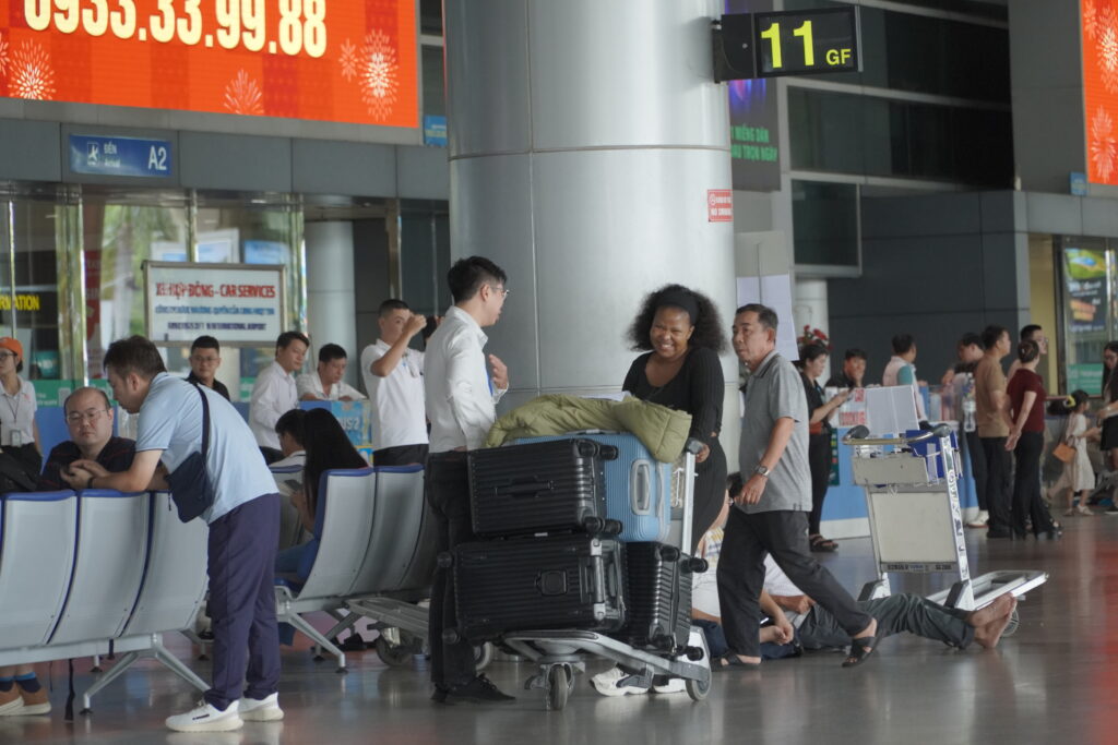 KissTour host helping a traveller with luggage at the airport arrival hall in Vietnam