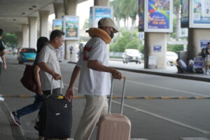 Passengers with suitcases walking outside Tan Son Nhat International Airport in Ho Chi Minh City, supported by Vietnam Fast Track Service for smooth arrival.