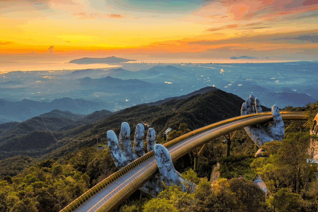 Golden Bridge at Ba Na Hills in Da Nang, Central Vietnam - an iconic pedestrian bridge held by giant stone hands, offering panoramic mountain and coastline views at sunrise.