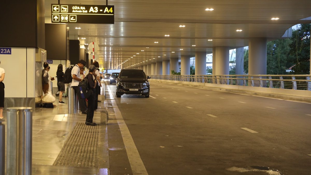 Lit arrivals kerbside with waiting cars after dark, where pickups happen when arriving in Vietnam at night
