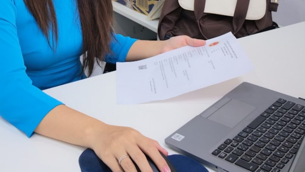 KissTour visa staff checking a printed application beside a laptop while handling an e-visa vs urgent visa request