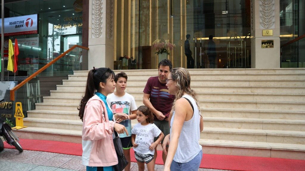 Tour guide welcoming a family with children outside their hotel in Ho Chi Minh City, Vietnam