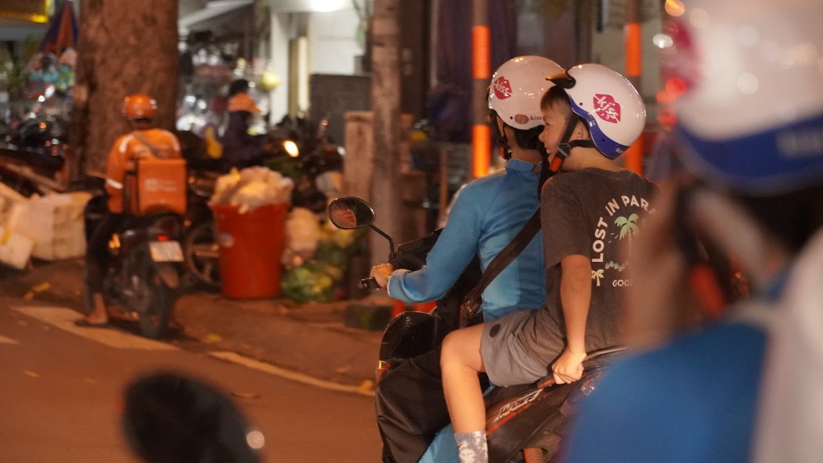 Getting around Saigon by motorbike: a KissTour guide rides with a young guest through District 1 at night