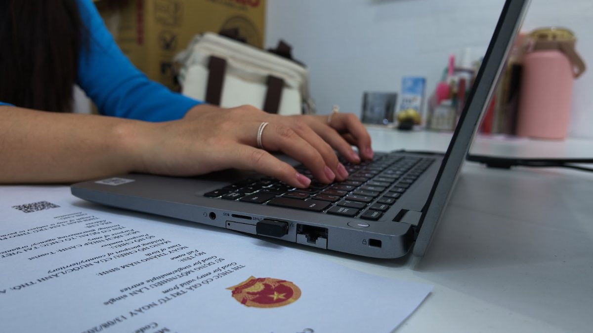 Printed Vietnam e-visa approval letter beside a laptop while the team works on a Vietnam visa in 1 hour request