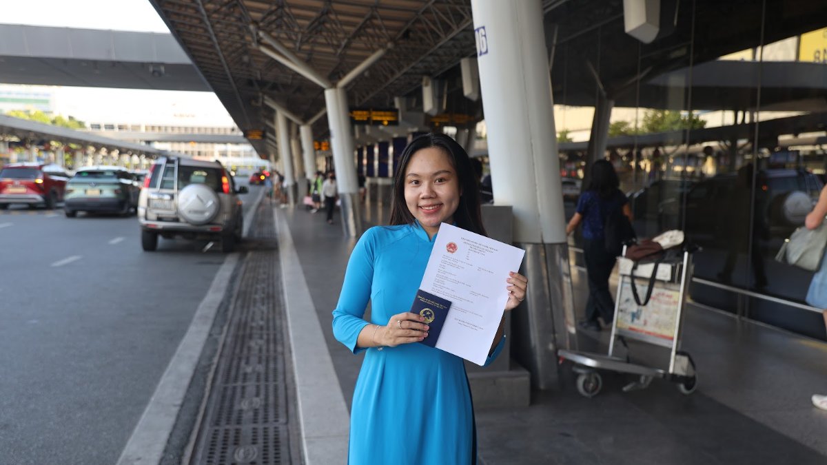 KissTour greeter in a blue ao dai with a visa document at the Tan Son Nhat airport pickup area