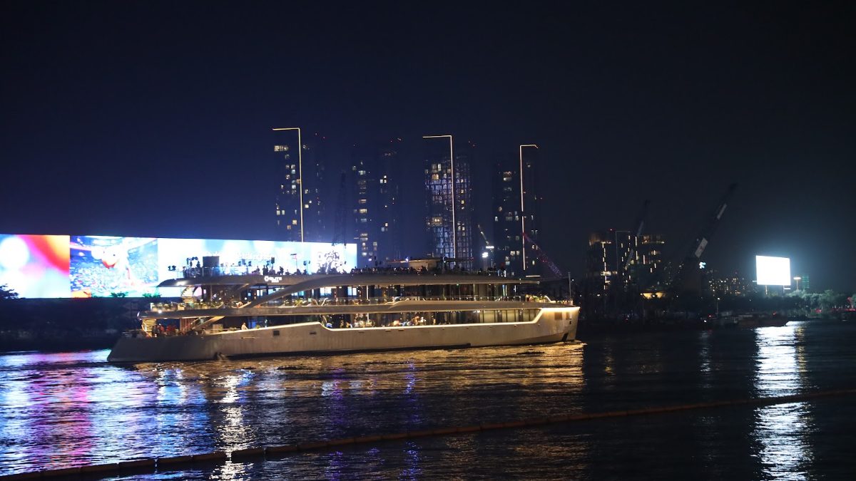 Dinner cruise boat on the Saigon River at night with LED billboard reflections on the water