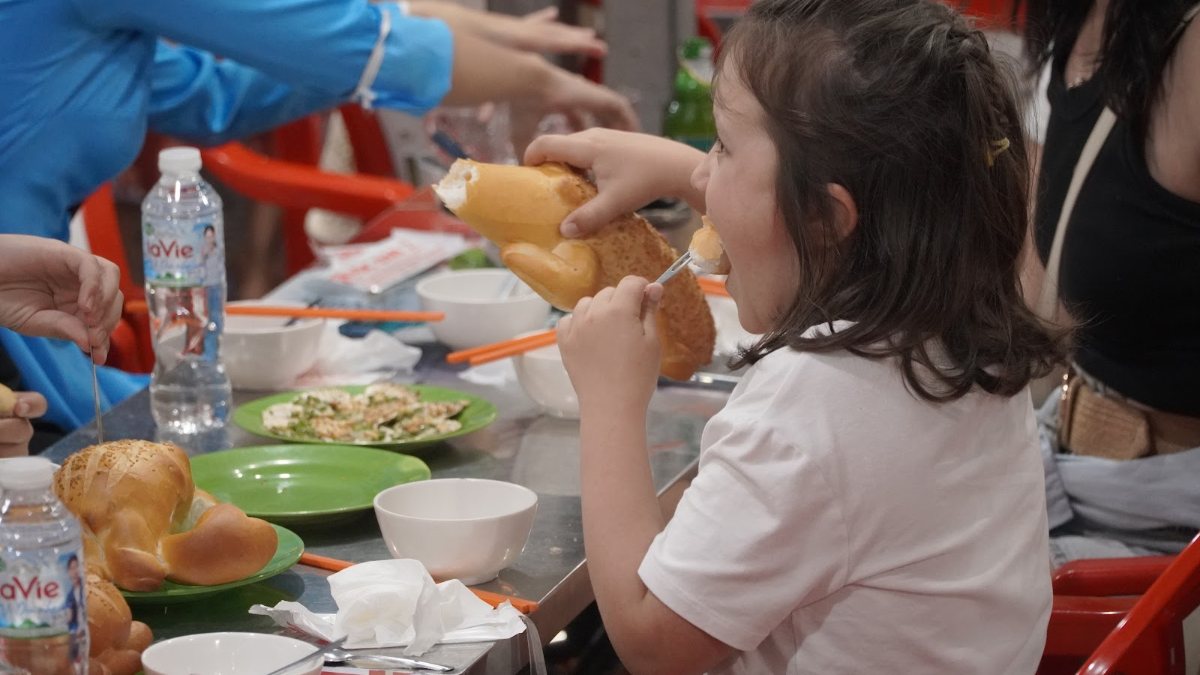 Guests and guides sharing plates at a plastic-stool table, the moment that makes a Saigon food tour worth it