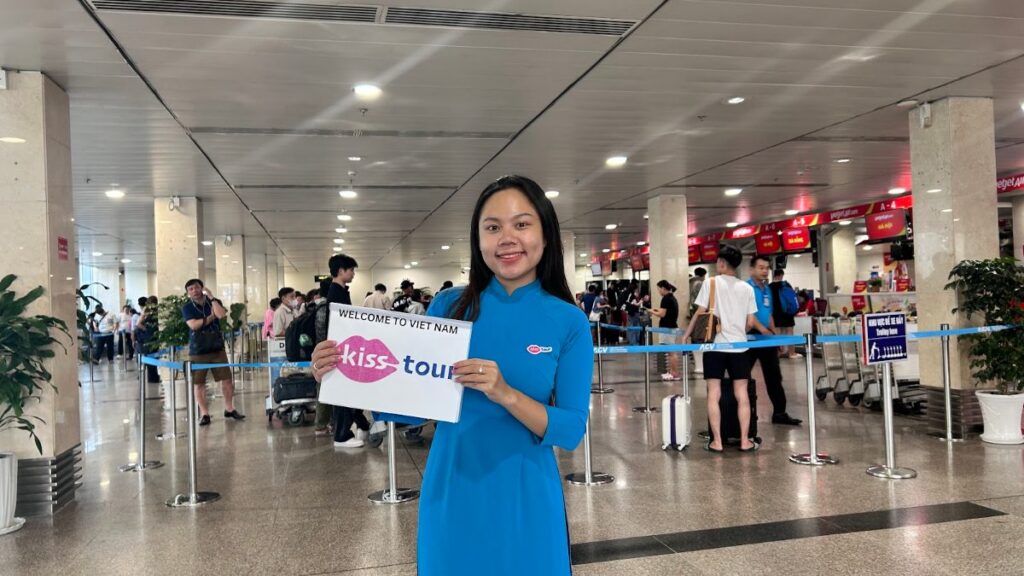 Vietnam visa fast track combo — KissTour greeter holding a welcome sign in the Tan Son Nhat arrivals hall