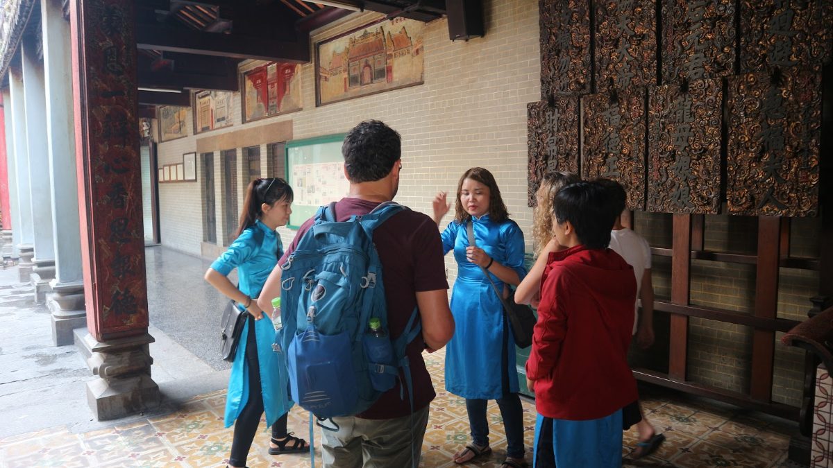 Exploring Vietnam with kids: KissTour guides in blue ao dai show a family around a Cho Lon temple in Ho Chi Minh City
