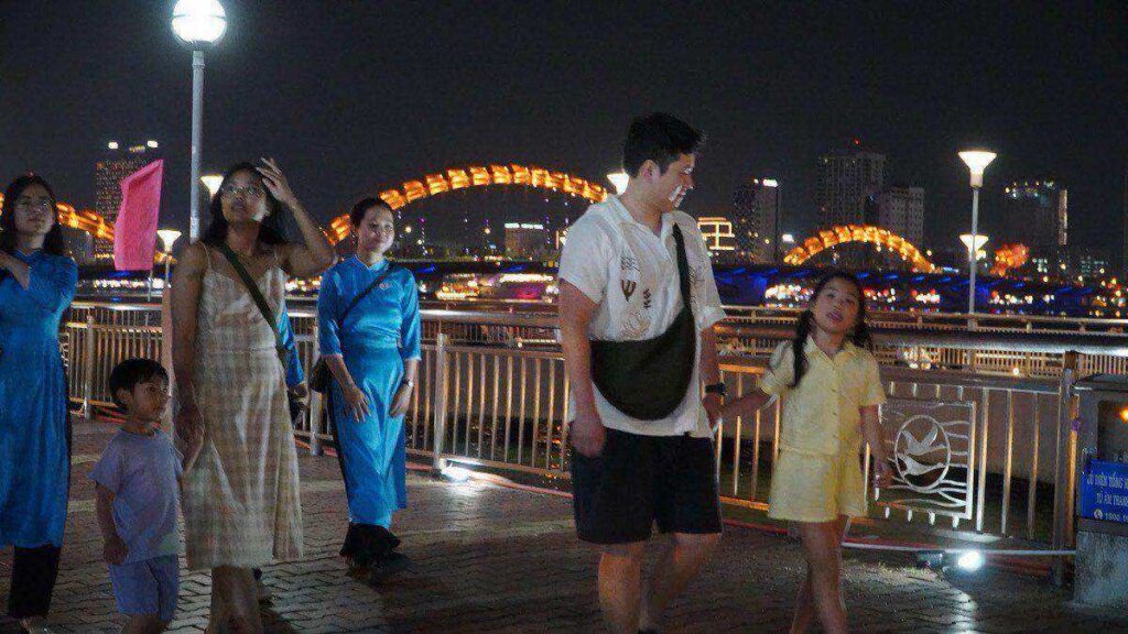 Da Nang riverfront with Dragon Bridge, family walking