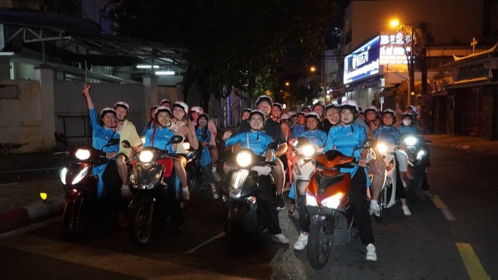Convoy of scooter riders on a Saigon street at night