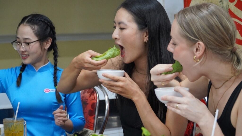 Guests happily eating fresh spring rolls with KissTour guide