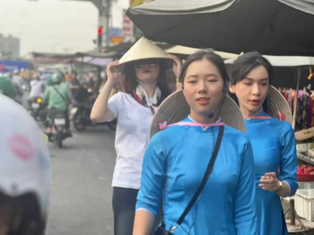 KissTour guides in blue ao dai standing with their scooters