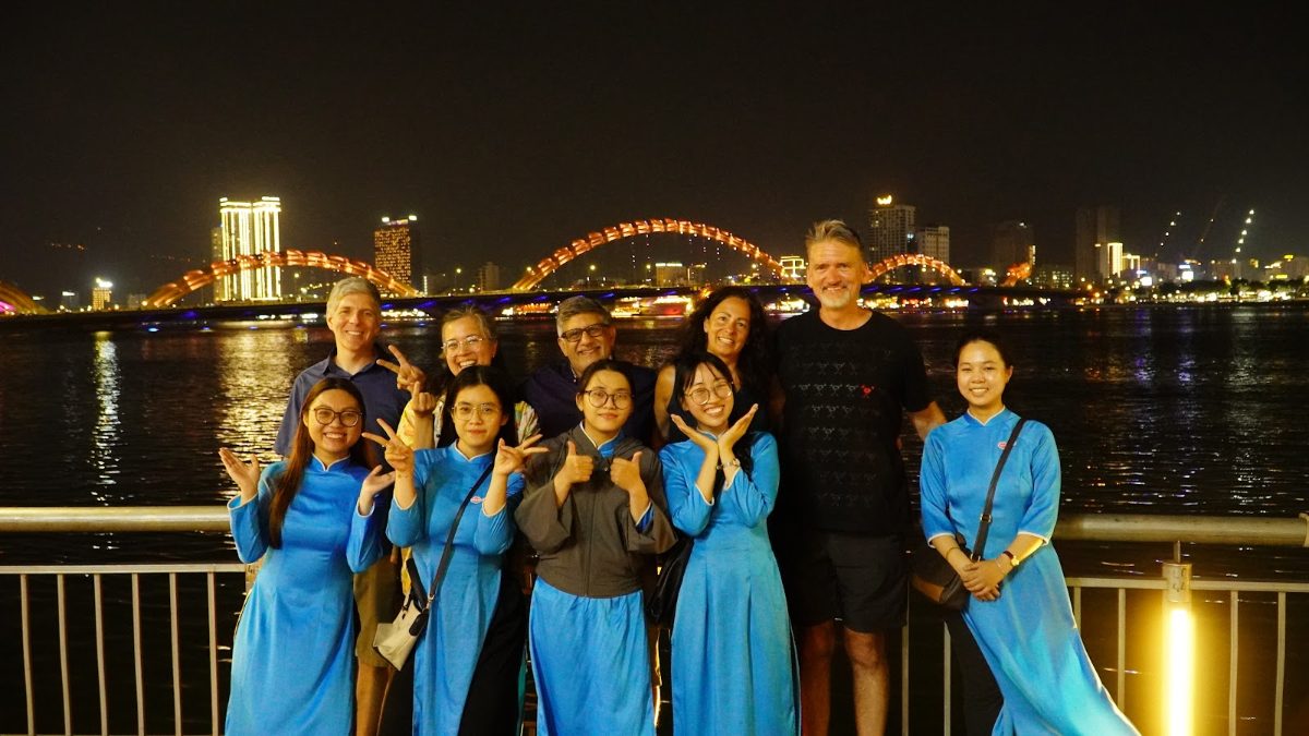 KissTour women riders and guests at the Dragon Bridge riverfront in Da Nang at night - deciding between Ho Chi Minh City or Da Nang