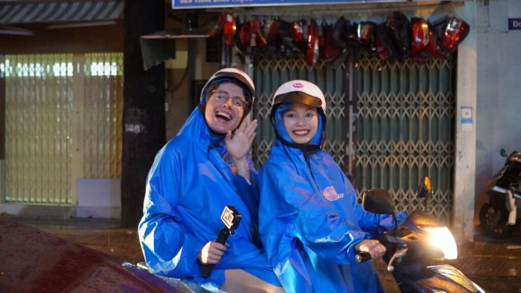 Guide and guest in rain ponchos on a scooter, Saigon