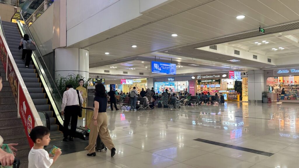 Arriving at Noi Bai airport: travellers with luggage trolleys in the arrivals concourse
