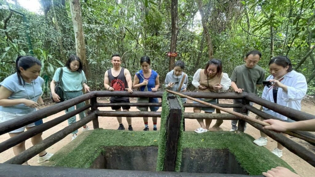 Travellers on a Cu Chi Tunnels day trip standing at a preserved tunnel section in the forest