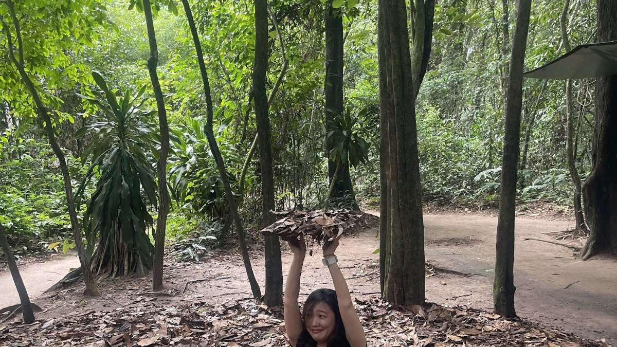 Guest lifting the hidden trapdoor entrance on a Cu Chi Tunnels day trip