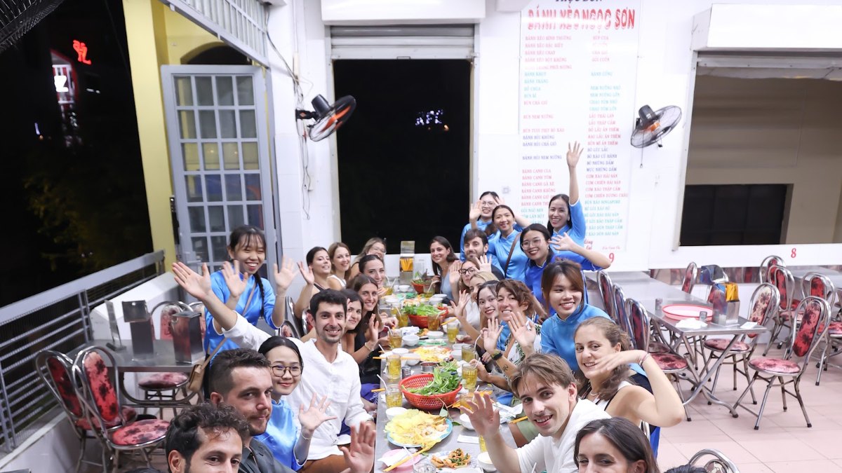 Food tour group eating together at long tables with their KissTour guides in Saigon