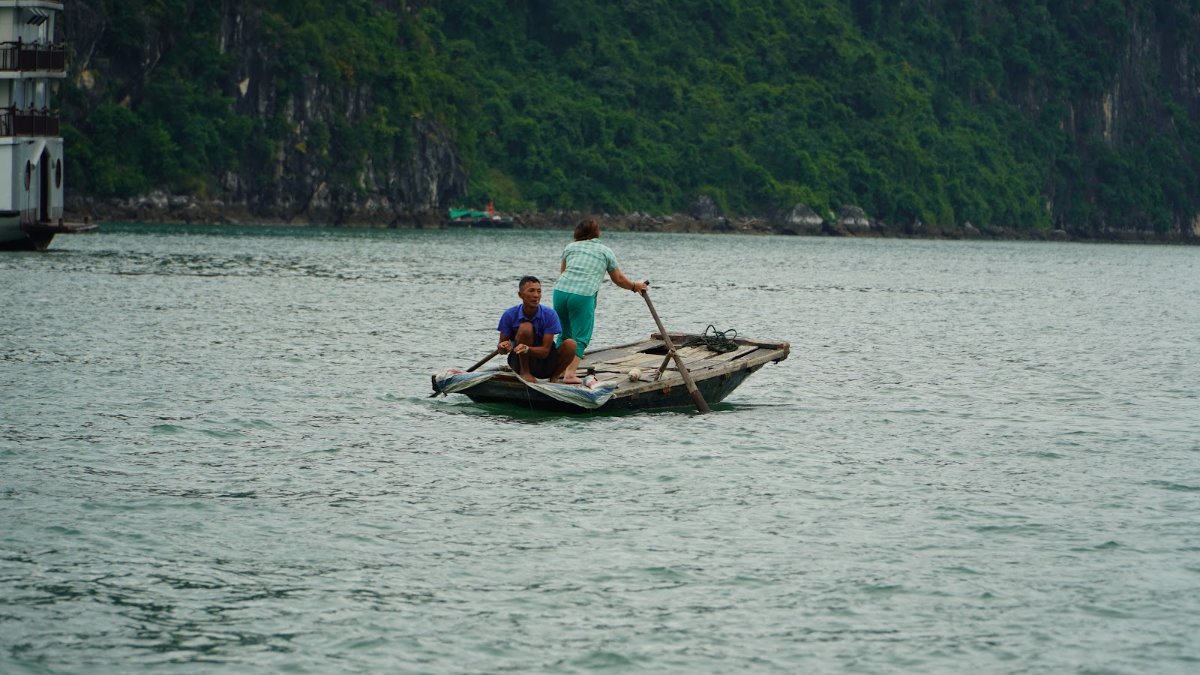 A bamboo rowboat gliding past limestone karsts in Ha Long Bay